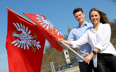 Dziewczyna i chłopak z dwiema flagami Mazowsza