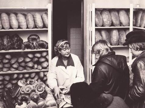 ekspiedientka obsuguje klientkę, która kupuje chleb i bułki drożdżowe