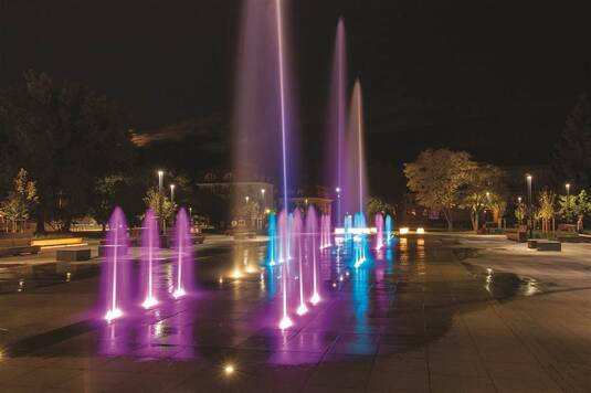 podświetlane fontanny na placu w mieście w nocy