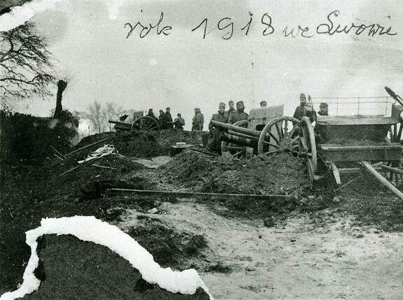 Fotografia archiwalna przedstawiająca grupę żołnierzy stojących przy działach.