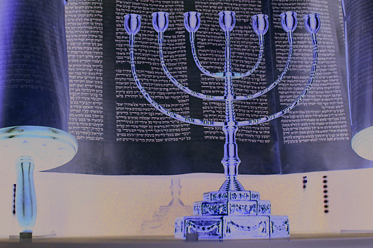 Siedmioramienny świecznik żydowski stoi na tle rozwinietego zwoju Tory
