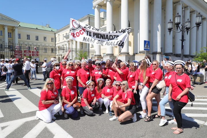 grupa strajkujących pielęgniarek przed Mazowieckim Urzędem Wojewódzkim w Warszawie z transparentem "Za ciężką pracę pieniądze nam się należą"