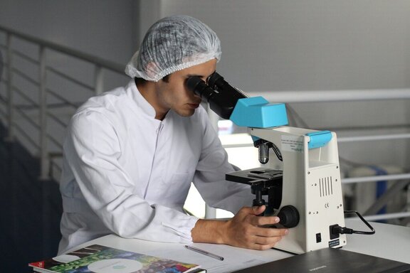 Mężczyzna w kiltu i czepku patrzy w mikroskop