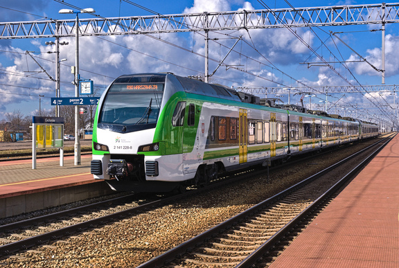Pociąg w zielono-biało- żółtych barwach  mazowieckiego przewoźnika na torze