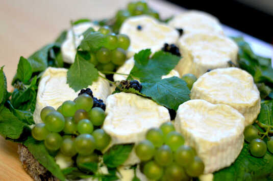 Kawałki białego sera poprzedzielane zielonym winogronem i liśćmi