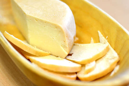 W drewnianej misce leży pokrojony żółty ser.