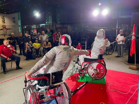 Dwaj sportowcy na wózkach podczas pojedynku szermierki