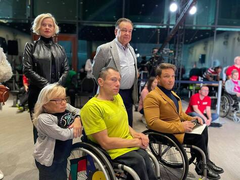 Marszałek pozuje do zdjęcia z dwoma sportowcami na wózkach inwalidzkich. Obok niego stoi Bożena Żelazowska