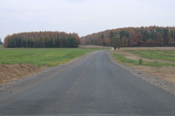 Droga asfaltowa wijąca się wśród pól i lasów