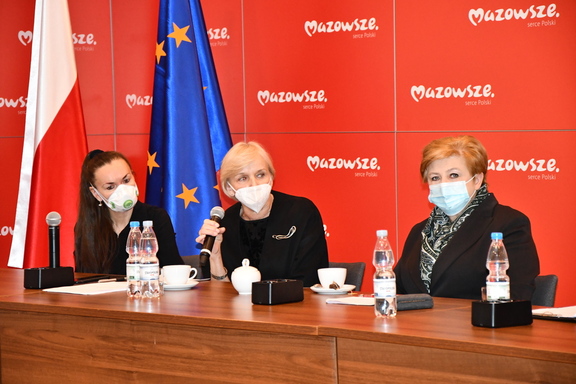 Elżbieta Lanc oraz dwie panie konsultantki - krajowa i wojewódzka siedzą przy stole konferencyjnym. Jedna z pań mówi do mikrofonu