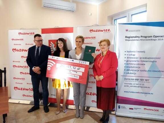 Elżbieta Lanc, Janina Orzełowska oraz beneficjenci pozują do zdjęcia z symbolicznym czekiem