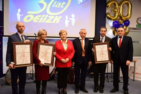 Elżbieta Lanc, przewodniczący Skolimowski, dyrektor Krusiewicz oraz trzech pracowników z dyplomami pozują do zdjęcia