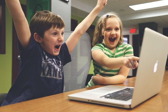 Zadowolone dzieci siedzące przed komputerem