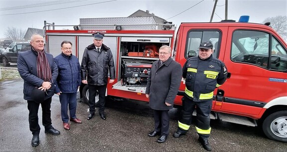 Marszałek i przewodniczący Leszek Przybytniak pozują do zdjęcia ze strażakami na tle nowo zakupionego wozu