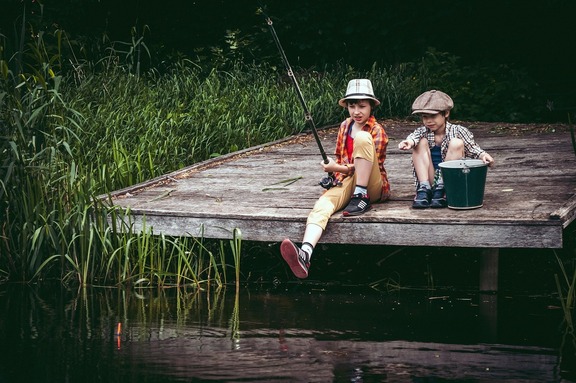 dwóch chłopców łowi ryby, siedzą na pomoście