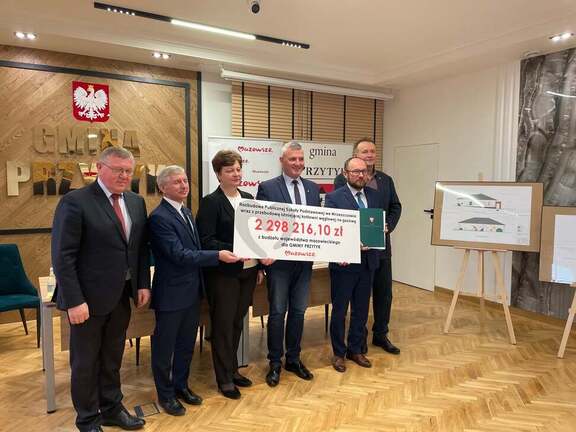 Wicemarszałek wraz z radnymi województwa mazowieckiego przekazują czek beneficjentom.