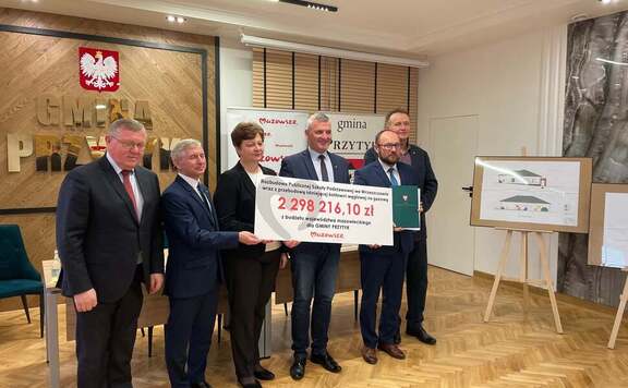 Wicemarszałek wraz z radnymi województwa mazowieckiego przekazują czek beneficjentom.
