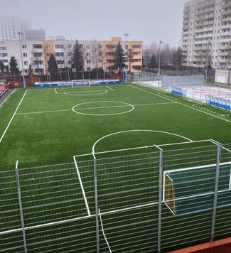 odnowione boisko do piłki nożnej. w tle bloki mieszkalne