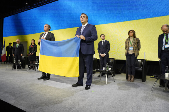 dwóch mężczyzn trzyma w rękach ukraińską flagę w barwach niebiesko żółtych