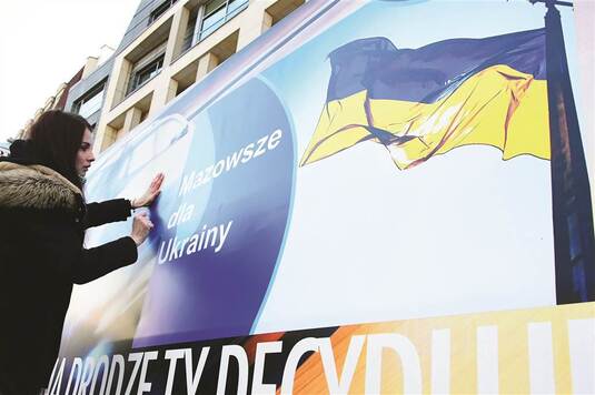 Dziewczyna zawiesza baner z napisem Mazowsze dla Ukrainy