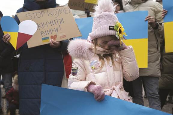 ludzie z banerami w dłoniach protestując przeciwko wojnie w Ukrainie, na pierwszym planie płaczące dziecko