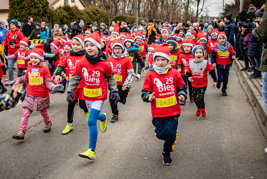 Dzieci biegną w maratonie. Każde dziecko ma taką samą koszulkę i czapkę Mikołaja