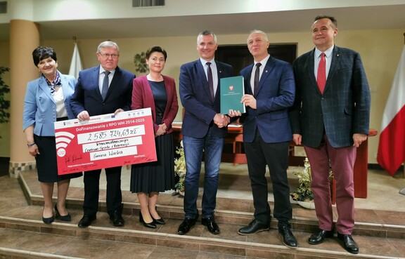 Wicemarszałek Rafał Rajkowski, dwóch radnych oraz przedstawiciele gminy pozują do zdjęcia z czekiem