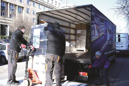 Mężczyźni pakują do ciężarówki dary dla Ukrainy.