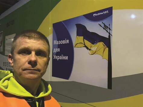 dyrektor Dariusz Grajda pozuje do zdjęcia na tle pociągu humanitarnego