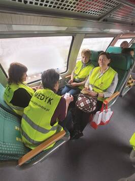 Cztery wolontariuszki siedzące naprzeciwko siebie w piętrowym wagonie pociągu humanitarnego.