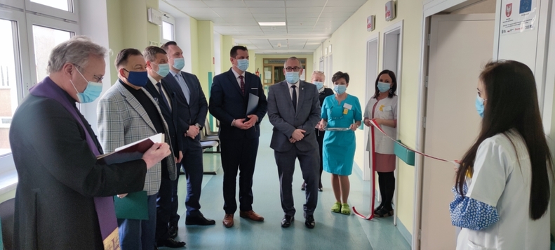 Marszałek, radni, przedstawiciele szpitala i dwie pielęgniarki stoją obok siebie na szpitalnym korytarzu