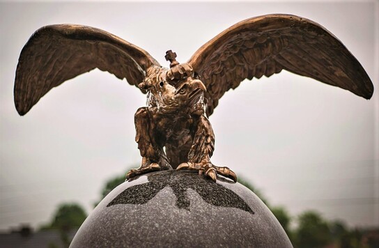 Metalowa rzeźba orła na granitowej kuli
