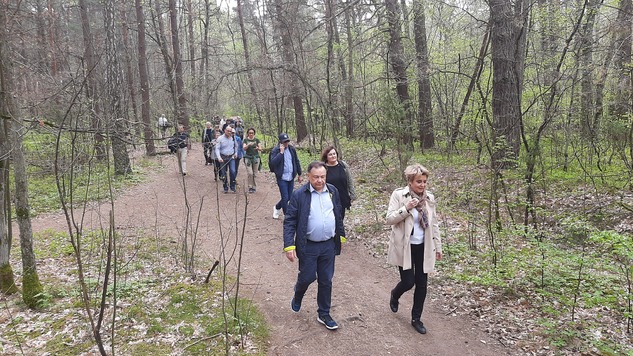 Członkowie spotkania idą leśną drogą. Na przedzie idzie marszałek