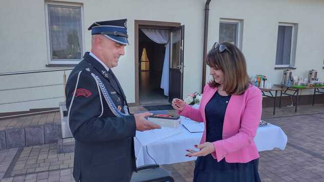 Członek zarządu województwa mazowieckiego Janina Ewa Orzełowska przekazuje kamerę termowizyjną jednostce OSP Krzesk. 