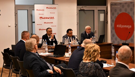 Marszałek Adam Struzik siedzi pomiędzy Ludwikiem Rakowskim a Tomaszem Matuszewski przy stole konferencyjnym ustawionym w podkowę. Po bokach siedzą inni uczestnicy spotkania