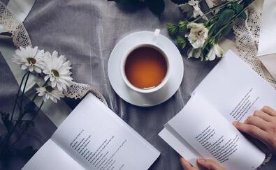 Filiżanka herbaty i otwarty tomik poezji na stole przykrytym obrusem