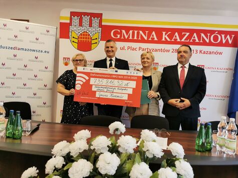 Cztery osoby stoją z dużym czekiem na tle napisu Gmina Kazanów.