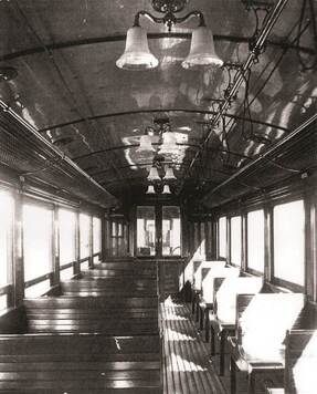 Zdjęcie przedstawia wnętrze pierwszego wagonu oświetlonego przez kryształowe żyrandole.