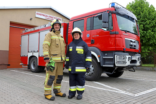 strażacy ochotnicy, kobieta i mężczyzna ubrani w ubrania ochronne 