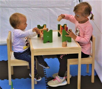 Dwoje dzieci bawi się drewnianymi zabawkami