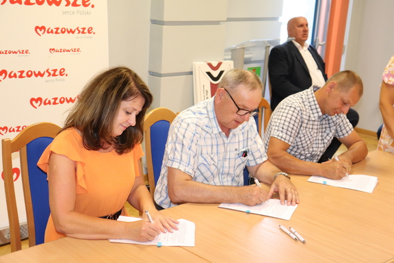 Od lewej Janina Ewa Orzełowska, beneficjenci programu Mazowsze dla melioracji podpisują umowę.