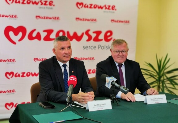 Wicemarszałek Rajkowski i radny Przybytniak siedzą przy stole konferencyjnym i udzielają wywiadu