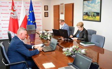 Trzy osoby z zarządu województwa mazowieckiego: Rafał Rajkowski, Elżbieta Lanc, Wiesław Raboszuk siedzą przy stole podczas zdalnego posiedzenia sejmiku.