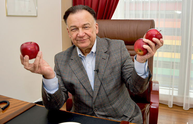Mężczyzna siedzi przy biurku i trzyma jabłka