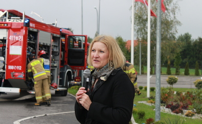 Kobieta udziela wywiadu. W tle widać strażaków przy samochodzie pożarowym