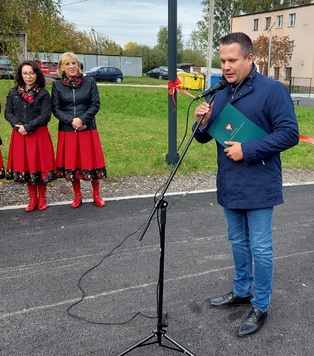 Przemówienie wiceprzewodniczącego Sejmiku Mirosława Adama Orlińskiego. W tle stoją dwie kobiety w czerwonych spódnicach.