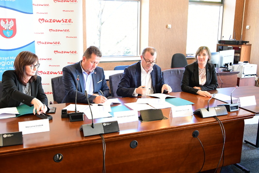 Cztery osoby przy stole konferencyjnym podpisują dokumenty 