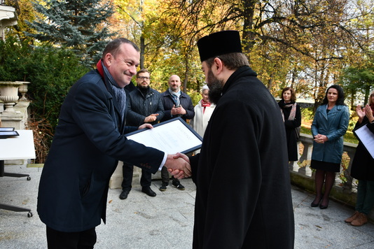Pop z parafii pw. św. Jana Klimaka w Warszawie odbiera certyfikat z rąk wicemarszałka Wiesława Raboszuka 