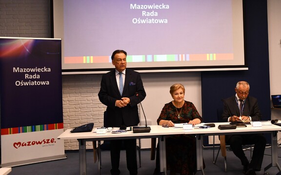 Marszałek przemawia na posiedzeniu rady. Stoi za stołem prezydialnym, obok siedzą Elżbieta Lanc i Krzysztof Skolimowski
