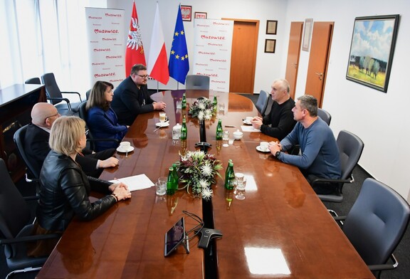 Przedstawiciele samorządu siedzą przy stole obrad. Po drugiej stronie jest dwóch przedstawicieli miast Miżhirja.